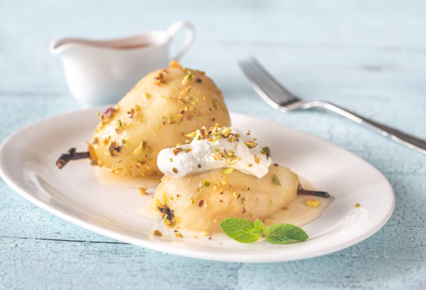 Poached pears on the white plate Poached pears in white wine with cream cheese and pistachios on the white plate pear dessert stock pictures, royalty-free photos & images