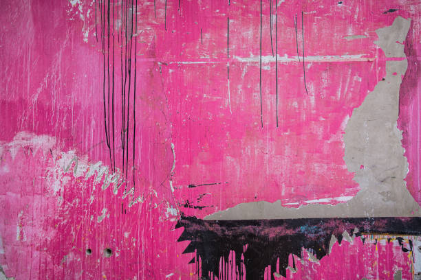 A pink wall that has weathered over time and had portions of it covered with black paint. Old and rustic pink and black background.