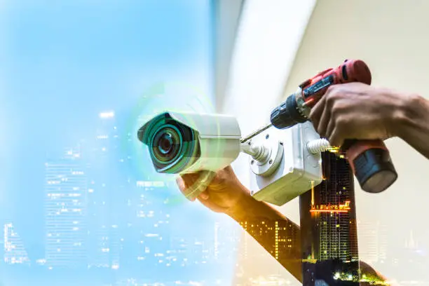 Photo of Double exposure technician installation CCTV camera on a pole , show signal , blurred background with an infographics city building landscape.