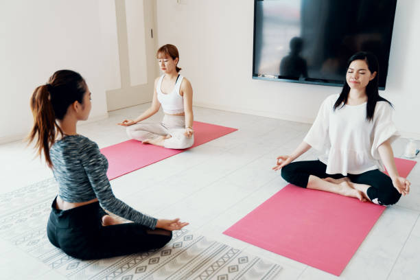 Millennial-aged women learning and practicing yoga stock photo