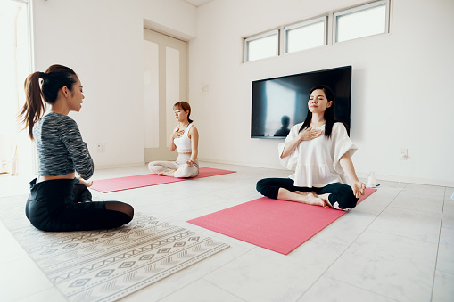 Millennial-aged women learning and practicing yoga together in a private home setting
