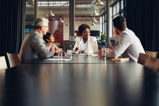 istock Diverse businesspeople sitting around a boardroom table discussing work 1180329390