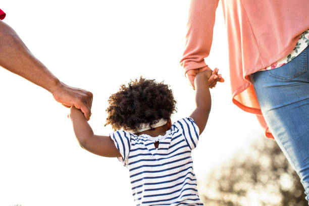 istock Little girl holding hands with her parents. 1180330581