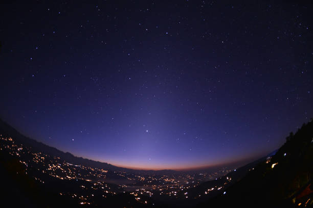 Nagarkot Valley in Nepal before sunrise Thousands of stars (Big Dipper constellation in the upper left corner together with Jupiter planet as the brightest “star” in the middle) and village lights seen from the Nagarkot Hill east of capital city of Kathmandu, Nepal. Parts of the Himalayan Range actually visible to the left with Gauri Shankar mountain dominating the horizon. The strange, vertical pillar of light in the middle of the picture is called “the zodiacal light” caused by dust from an ancient comet from the Jupiter Group. nagarkot photos stock pictures, royalty-free photos & images