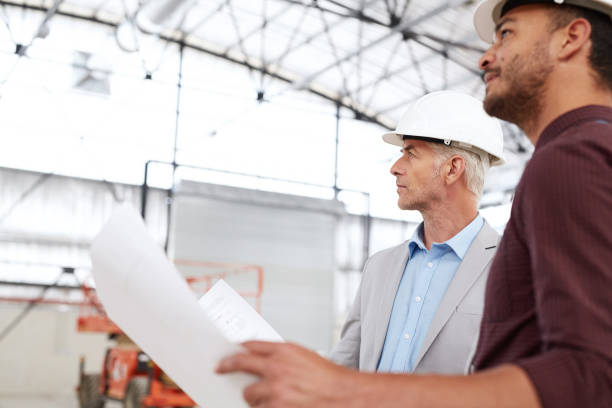 istock Two engineers reading blueprints together inside of a building site 1180342457