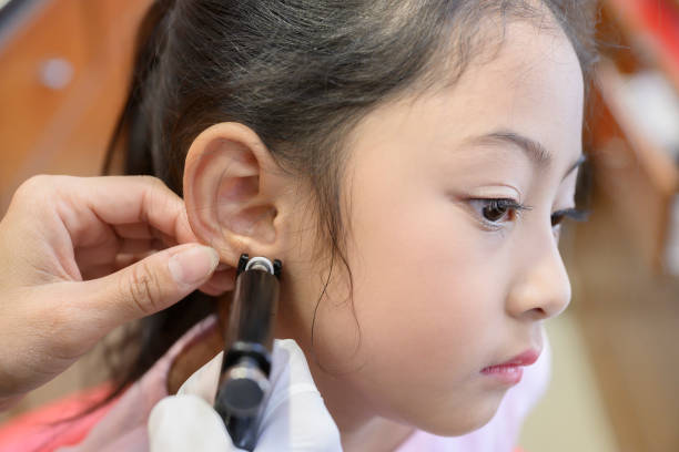 istock Adorable little asian girl having ear piercing process. 1180343578