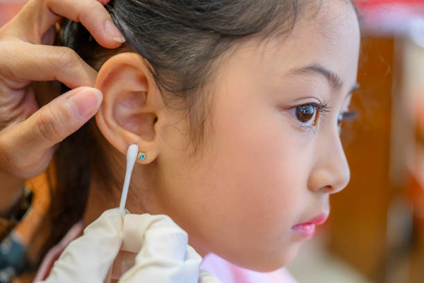 adorable little asian girl having ear piercing process. - asian ethnicity fashion model beautiful luxury imagens e fotografias de stock