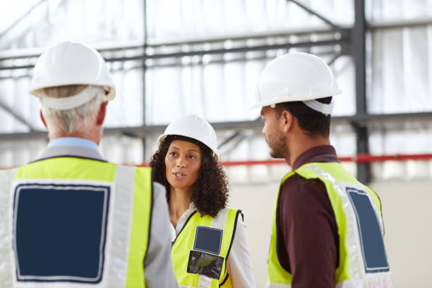 istock Female building engineer talking with coworkers in a warehouse 1180343900