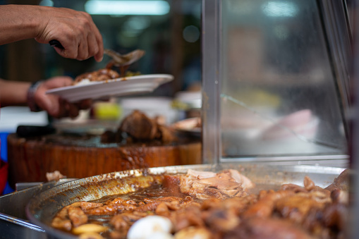 Hawker preparing Thai style stewed pork leg meal on street