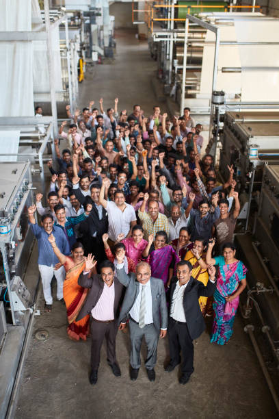 Proud Staff of Mumbai Textile Factory Celebrating Success High angle view of proud staff at Mumbai dyeing and printing mill looking at camera from factory floor and celebrating corporate success. organized group photos stock pictures, royalty-free photos & images