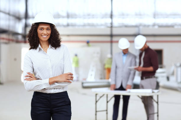 istock Smiling young building engineer with colleagues working behind her 1180346832