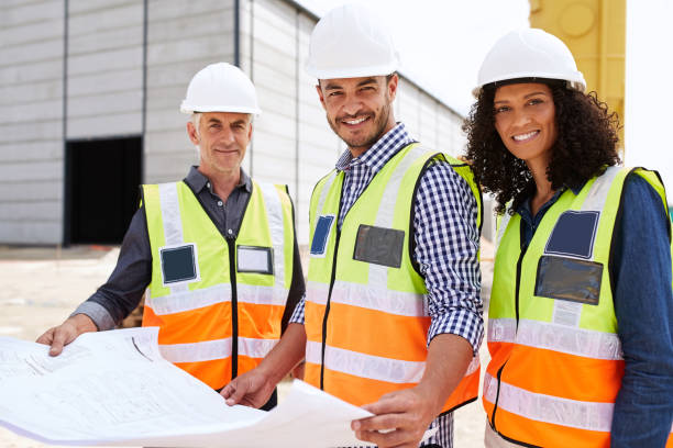 istock Smiling construction engineers holding building plans on a building site 1180347682