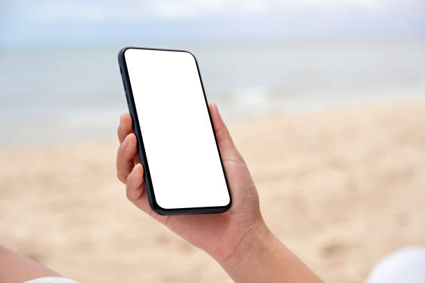 istock hands holding black mobile phone with blank desktop screen by the sea 1180347736
