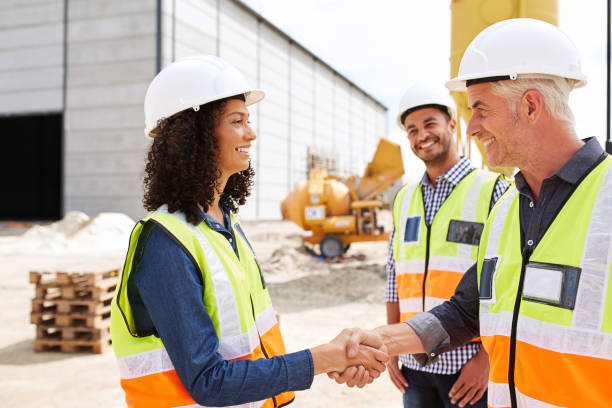 istock Smiling construction engineers shaking hands together on a building site 1180347878