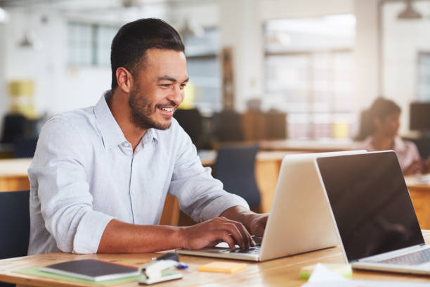 istock Smiling young businessman working on a laptop in an office 1180351777