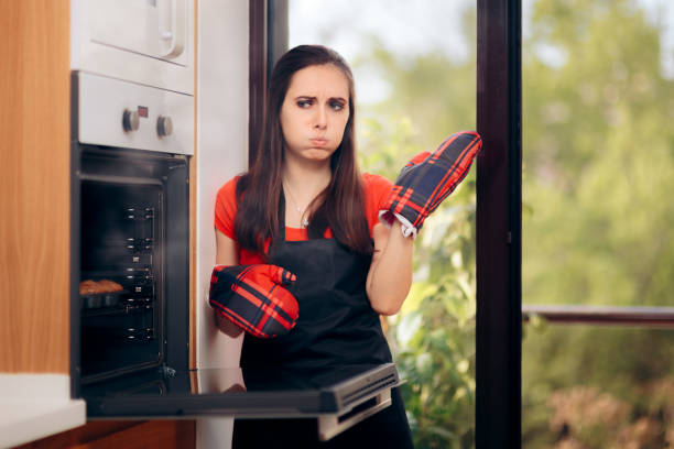 frau scheitert beim backen einige muffins im ofen - back lit stock-fotos und bilder