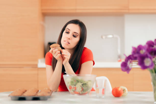 femme mangeant un gâteau au lieu des pommes ou de la salade - attractive female indoors lifestyles clean photos et images de collection