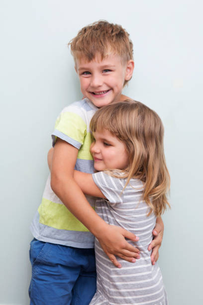 istock Cute happy siblings hugging cuddling feeling love and connection on a gray background. children good relationships 1180352689