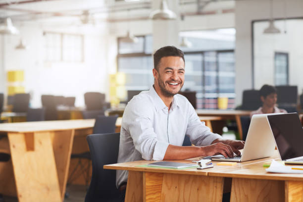 istock Smiling young businessman working on a laptop at his desk 1180352953