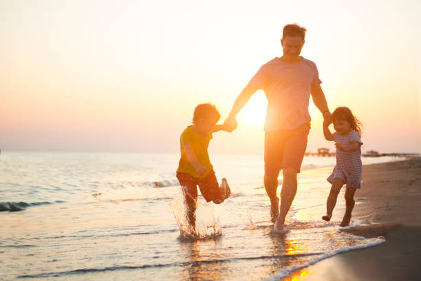 happy  family father and two children playing on the beach  run at the sunset time. - vacations two generation family caucasian friendship imagens e fotografias de stock