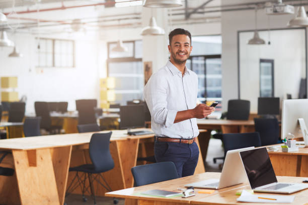 istock Young businessman reading texts on his cellphone in an office 1180354123