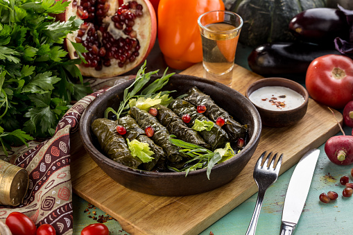 Un plato de deliciosas hojas de uva rellenas con carne molida y granada en tabla de madera photo
