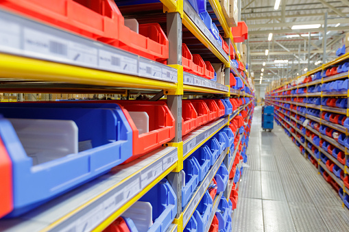 Diminishing perspective of warehouse racks filled with red and blue trays