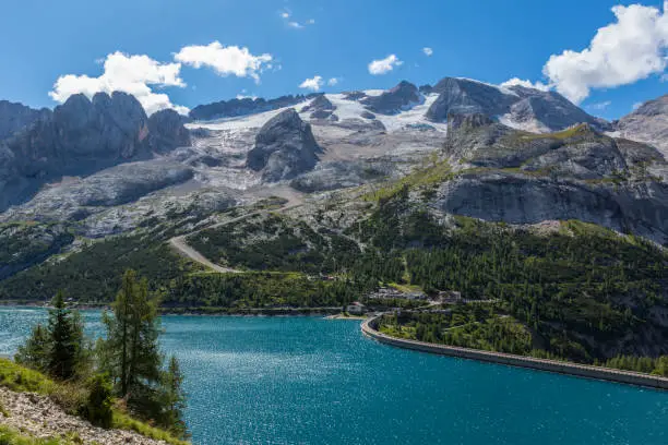 lake Fedaia and Marmolada mountain in italian dolomites, cloudy blue sky