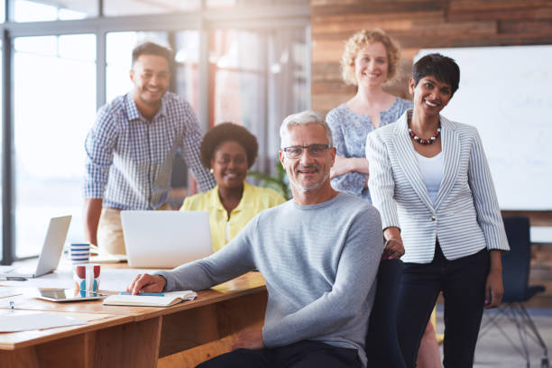 istock Smiling businesspeople working at a table in an office boardroom 1180360496