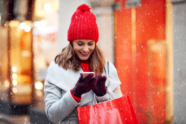 mooie vrouw die mobiele telefoon tijdens het winkelen in de winter - christmas people stockfoto's en -beelden