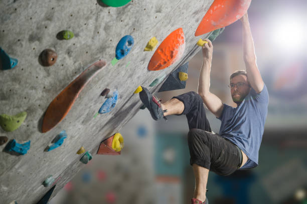 istock young active sport caucasian man with beard and glasses climbing on gym wall during bouldering workout 1180363312