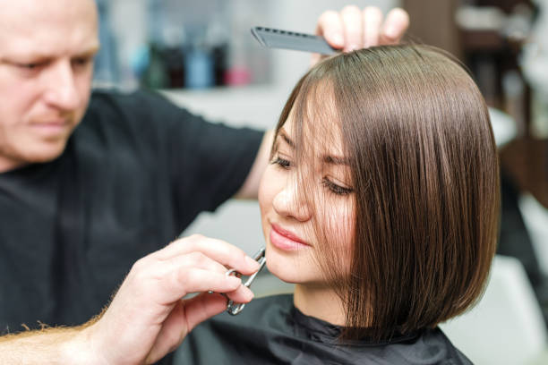 Young woman and hairdresser cutting hair tips at salon Stylist is cutting woman hair and making new hairdress in salon. Hairdresser cutting client's hair in beauty salon. Hairstyle and people concept Combing stock pictures, royalty-free photos & images