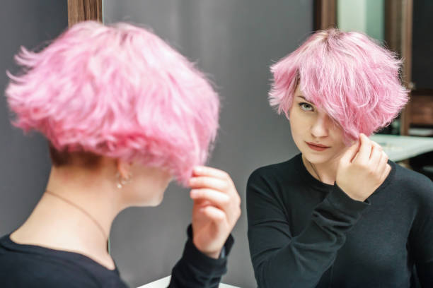 Pink hair woman with a short hair is looking at the mirror Pink hair woman with a short hair is looking at the mirror. Beauty concept. short weave hairstyles stock pictures, royalty-free photos & images