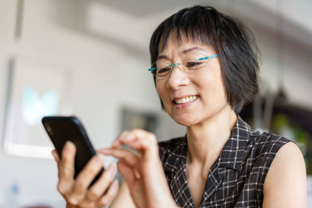 mujer asiática senior usando un teléfono inteligente - women telephone senior adult on the phone fotografías e imágenes de stock