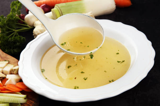 istock Broth with carrots, onions various fresh vegetables in a pot - colorful fresh clear spring soup. Rural kitchen scenery vegetarian broth 1180368389