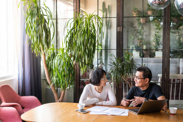 asiatisches paar spricht über das design ihres neuen hauses - indoors blueprint smiling built structure stock-fotos und bilder