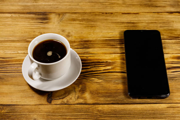 istock Cup of coffee and smartphone on a wooden table 1180370604