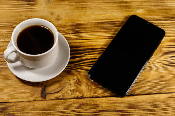 istock Cup of coffee and smartphone on a wooden table 1180370606