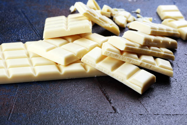 istock white broken chocolate and cocoa bar. Pieces of white chocolate on rustic background 1180370937