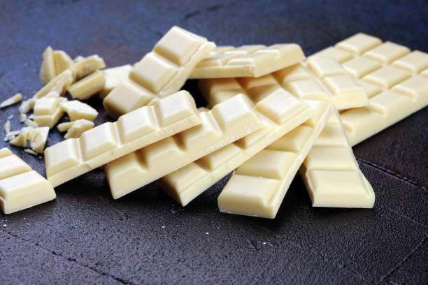 istock white broken chocolate and cocoa bar. Pieces of white chocolate on rustic background 1180371014