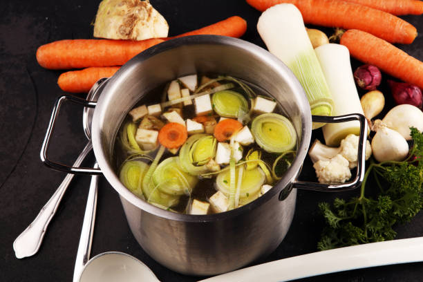 istock Broth with carrots, onions various fresh vegetables in a pot - colorful fresh clear spring soup. Rural kitchen scenery vegetarian broth 1180373038
