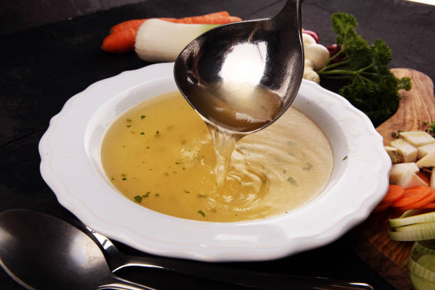 istock Broth with carrots, onions various fresh vegetables in a pot - colorful fresh clear spring soup. Rural kitchen scenery vegetarian broth 1180373206