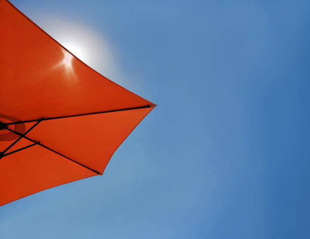 fond bleu lumineux de ciel avec un parapluie rouge de plage. - outdoor chair beach chair umbrella photos et images de collection