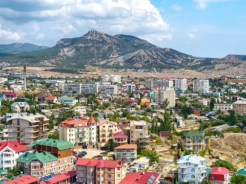 Aerial view of city Sudak. Houses of citizens and hotels for tourists. Beautiful mountain and blue sky on the background.