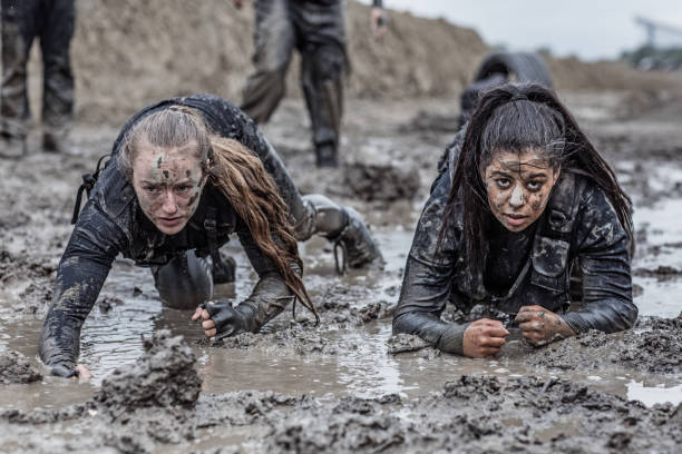 military mud run crawling exercise for two women - mud run imagens e fotografias de stock