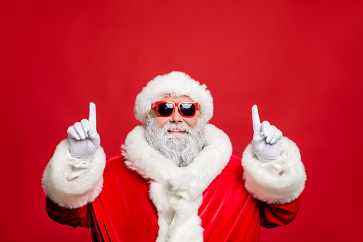 Foto de cerca de alegre divertido hipster padre de Navidad indican resolución de año nuevo seguir las ventas mágicas de hadas usar gorra elegante sombrero gafas gafas aisladas sobre el fondo de color rojo photo