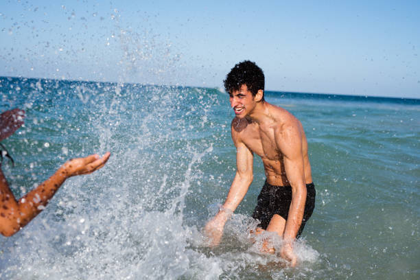 istock Young man splashing a girl with water 1180384481