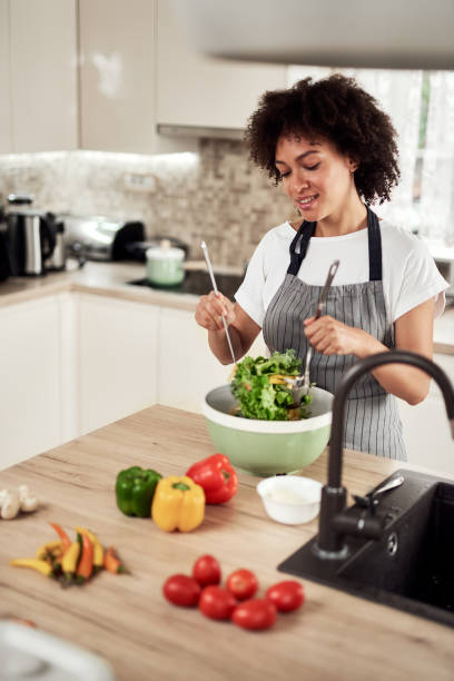 istock Woman mixing vegetables in bowl while standing in kitchen. 1180386767