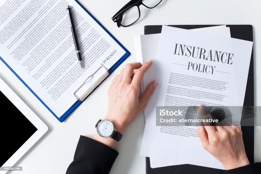 Business woman examining insurance policy Business woman showing insurance document over white desk at office Insurance Stock Photo