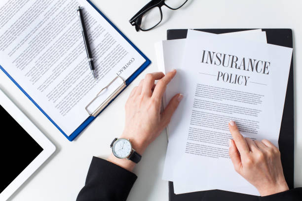 Business woman examining insurance policy Business woman showing insurance document over white desk at office insurance stock pictures, royalty-free photos & images